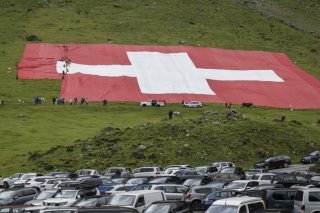 Déchiré par une bourrasque de vent sur son côté gauche, le drapeau géant est en cours de réparation. KEYSTONE/GIAN EHRENZELLER